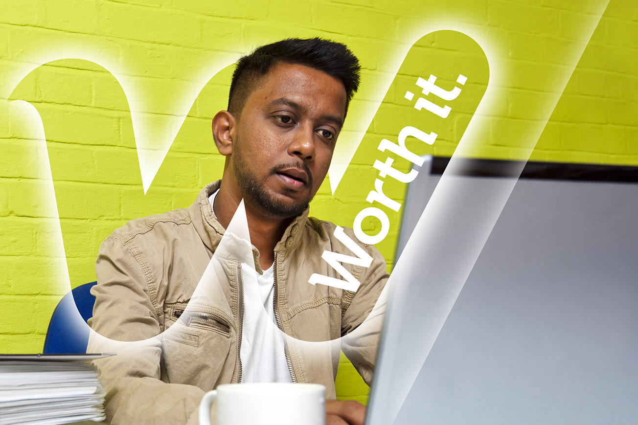 A man sat at a desk working on a computer