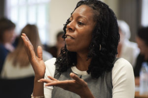 A lady doing sign language in a room of other people