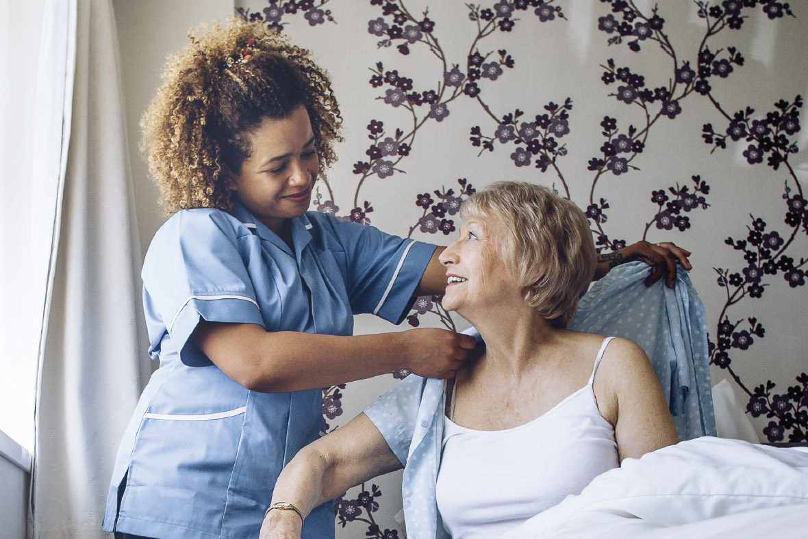 A nurse helping an elderly woman in bed.