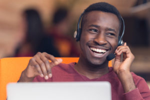 A young adult listening to something on his headphones sat at a laptop