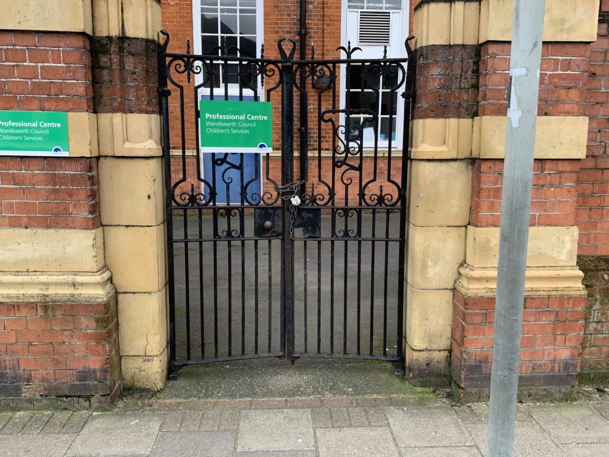 A usual business building with a red brick exterior and a green sign.