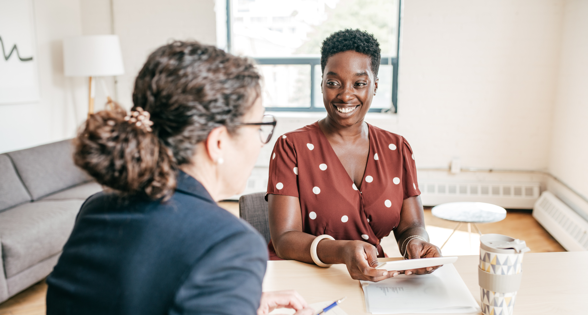 Two women at a table in an office engage in Level One conversation, displaying effective mentorship skills.