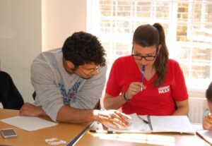 Two people sat at a desk helping each other complete a learning task at Ripe Learning.