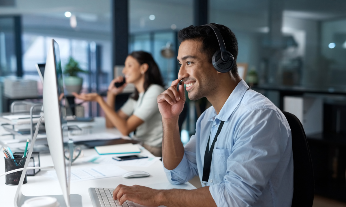 Smiling man with a headset, speaking to a customer and helping them